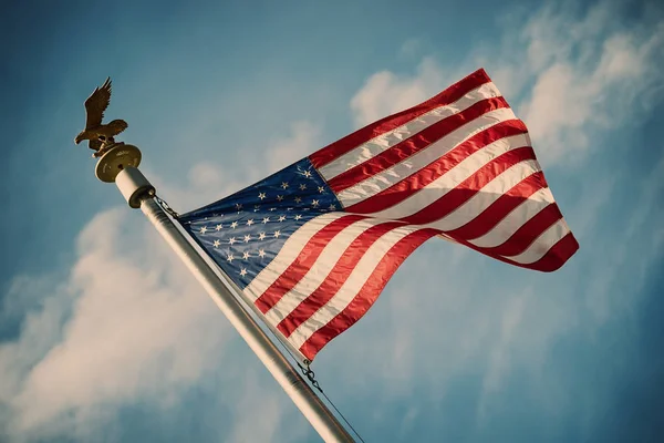 Bandera americana en poste ondeando en el viento contra el cielo azul — Foto de Stock