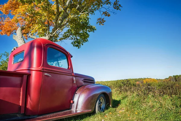 Eski kırmızı çiftlik kamyon sonbahar ağacın altında park etmiş. — Stok fotoğraf