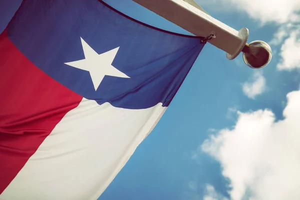 Texas state flag against blue sky and white clouds