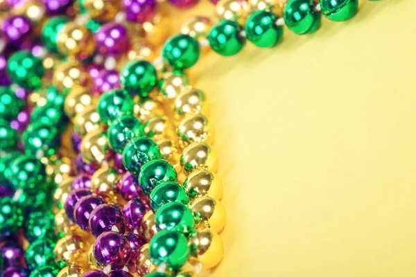 Mardi Gras beads against yellow background — Stock Photo, Image