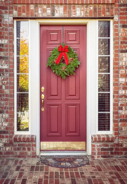 Couronne de Noël en sapin baumier sur une porte rouge — Photo