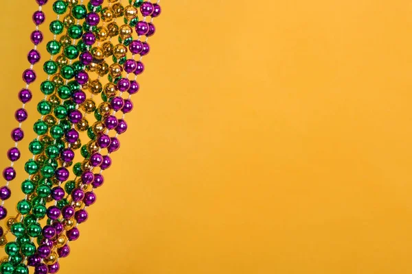 Mardi Gras kralen tegen gouden gele achtergrond — Stockfoto