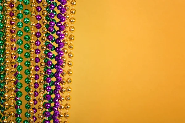 Mardi Gras beads against golden yellow background — Stock Photo, Image