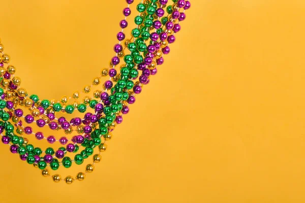 Mardi Gras beads against yellow background — Stock Photo, Image