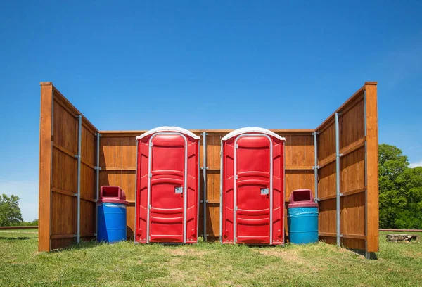 Два красных переносных туалета в парке — стоковое фото