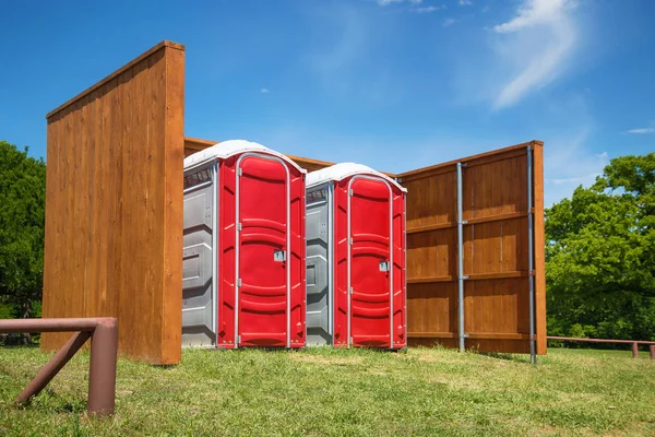 Två röda portabla toaletter i en park — Stockfoto