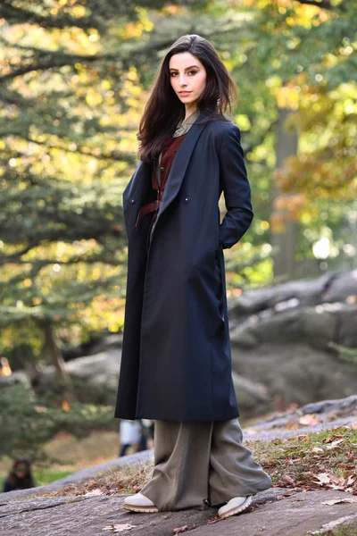 Beautiful young woman in elegant coat walking outdoors in autumn enjoying nature and weather.