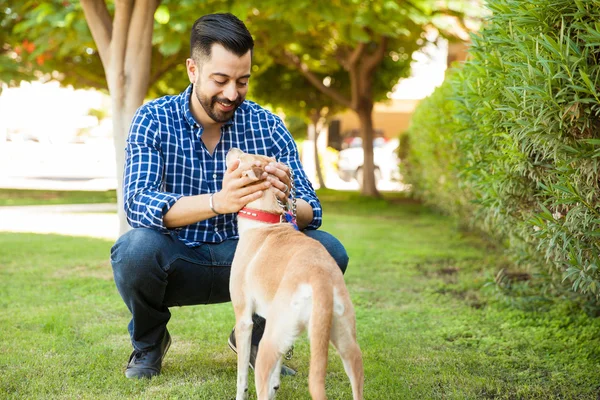 Человек с бородой, кормящий собаку — стоковое фото
