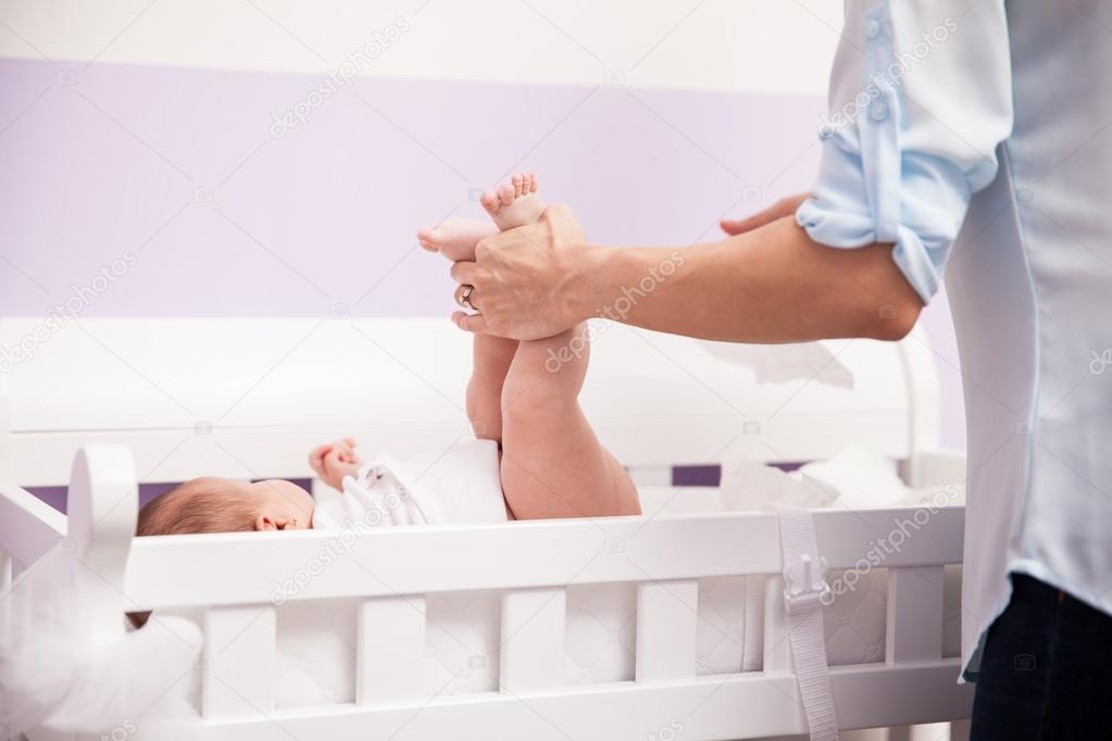 Woman lifting her newborn baby's legs 