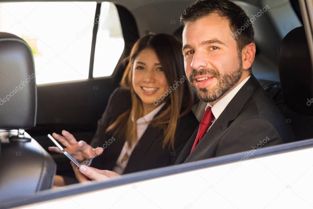 businessman and woman sitting in the backseats 