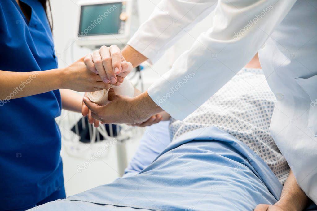 Doctors bandaging patient arm