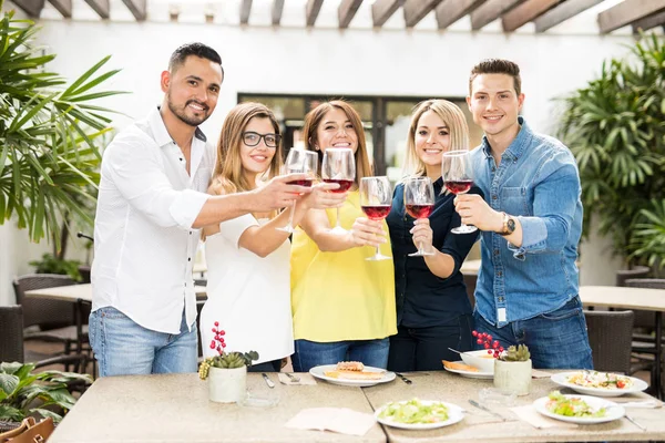 Freunde stoßen mit Wein an — Stockfoto