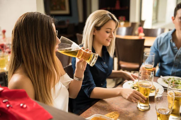 Молода жінка п'є пиво з друзями — стокове фото