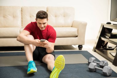 Egzersiz yaparken bir akıllı telefon kullanan adam