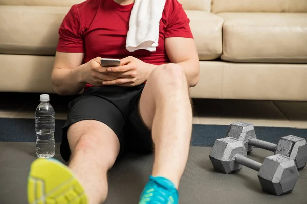 Homem usando um smartphone durante o exercício — Fotografia de Stock