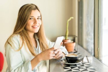 Smartphone kullanarak ve kahve içme kadın 