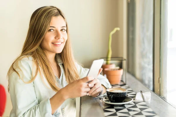 Wanita menggunakan smartphone dan minum kopi — Stok Foto