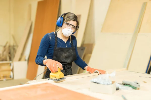 Carpintero femenino que usa lijadora en la carpintería —  Fotos de Stock