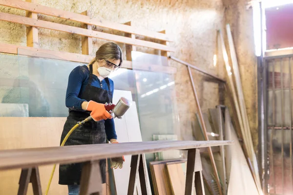 Женщина рисует стол в деревообрабатывающей мастерской — стоковое фото