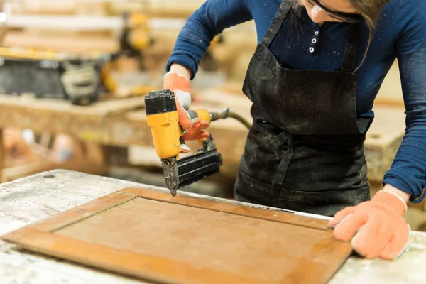 Female carpenter using nail gun — Stock Photo, Image