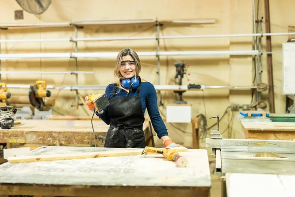 Carpinteiro feminino usando lixadeira na marcenaria — Fotografia de Stock