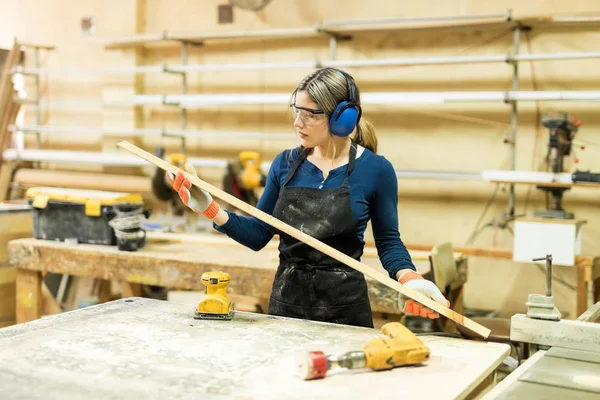 Vrouw onderzoeken sommige hout op het werk — Stockfoto