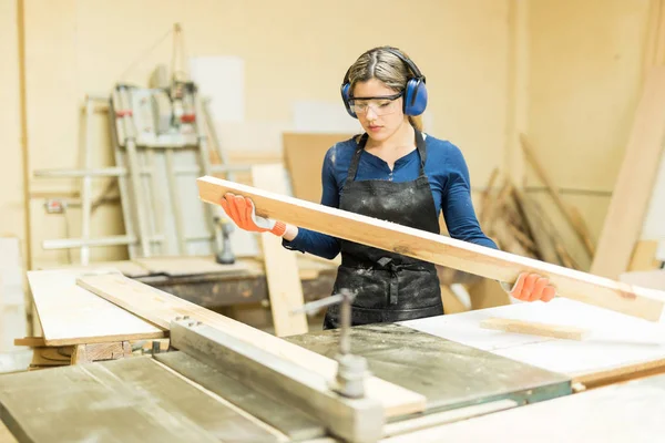 Tischlerin betrachtet Stück Holz — Stockfoto