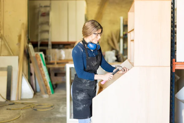 Female carpenter hammering some nails — Stock Photo, Image