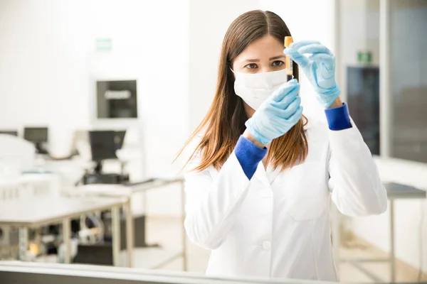 Química femenina mirando un tubo de ensayo — Foto de Stock