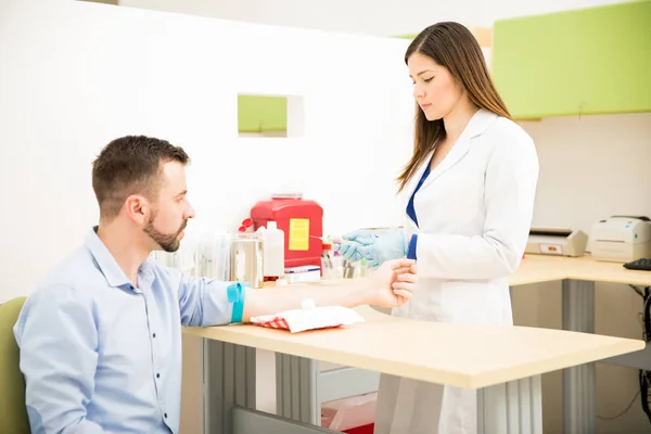 Médico sosteniendo una jeringa delante del paciente — Foto de Stock