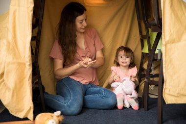 Anne yeni yürümeye başlayan çocukla oynuyor.