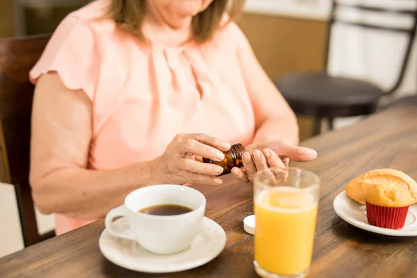 Granny taking medication with breakfast — Stock Photo, Image