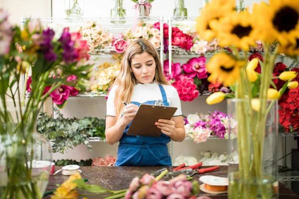 Флорист перевіряє доставку квітів у її магазині — стокове фото
