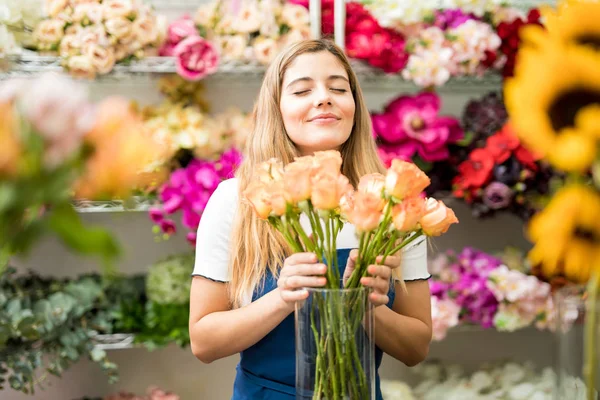 Female florist smelling a bunch of roses — Stock Photo, Image