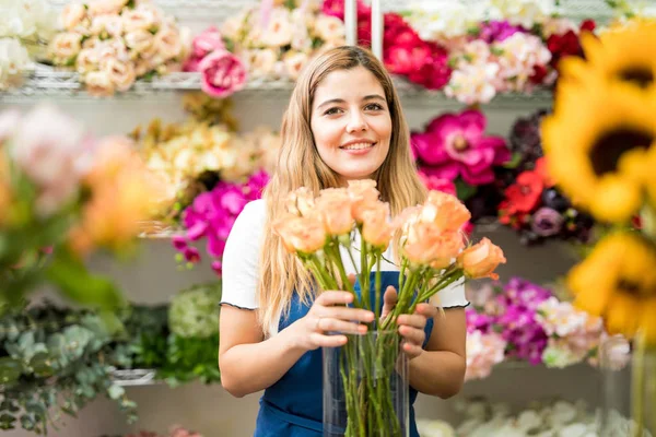 Cute worker putting together a bunch of roses — Stock Photo, Image