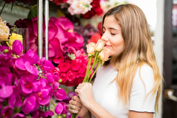 Sweet woman smelling flowers in a store — Stock Photo, Image