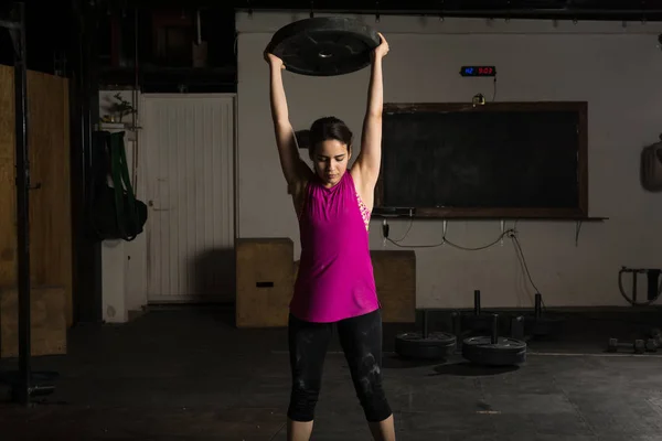 Mujer haciendo ejercicio con una placa de peso —  Fotos de Stock