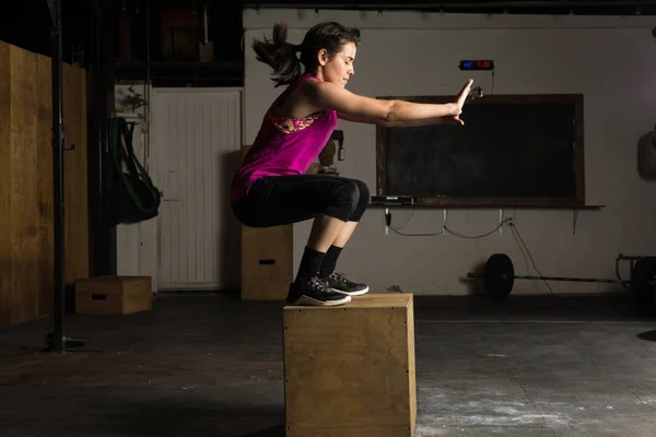 Спортивная женщина делает прыжки в коробку — стоковое фото