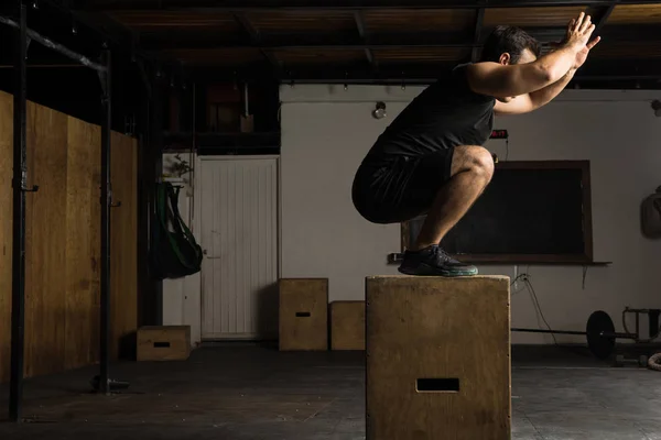 Hombre activo haciendo saltos de caja en un gimnasio — Foto de Stock