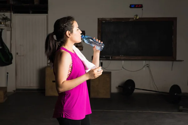 Женщина пьет воду в спортзале — стоковое фото