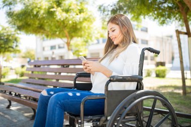 Tekerlekli sandalye ile bir smartphone kadında