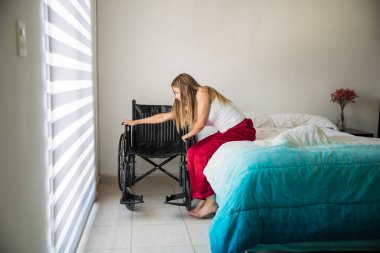 Felçli kadın tekerlekli sandalyede oturmak için çalışıyor