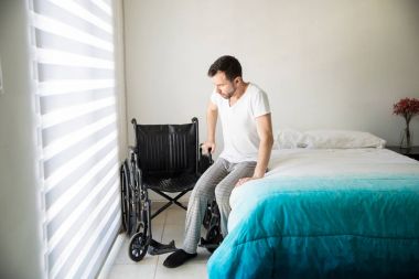 Onun tekerlekli sandalye üzerinde oturmak çalışan adam