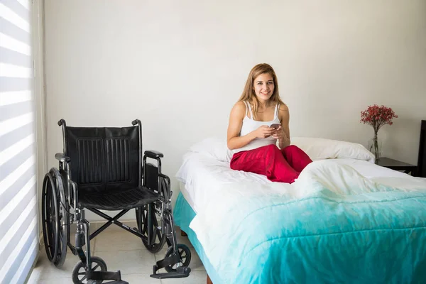 Leuke vrouw in rolstoel met smartphone — Stockfoto