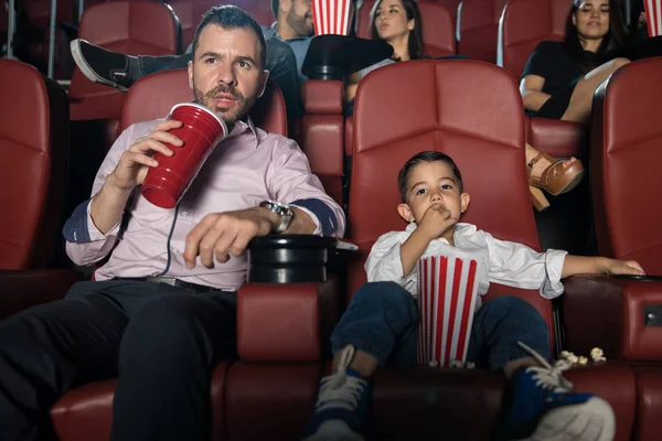 Homme et fils regardant un film au cinéma — Photo