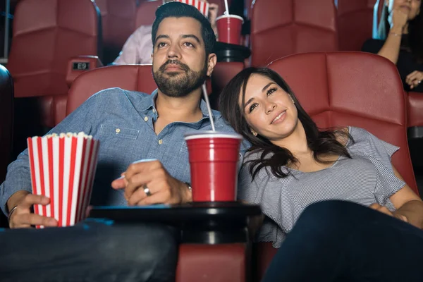 Woman with head on boyfriends shoulder at cinema