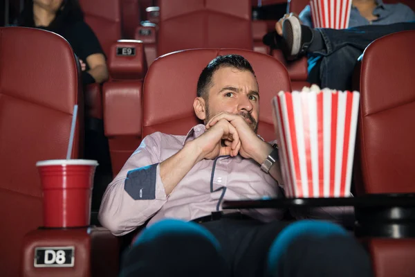 Scared man watching movie at cinema