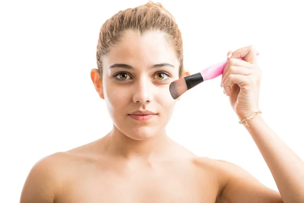 Jovem mulher colocando blush no rosto — Fotografia de Stock