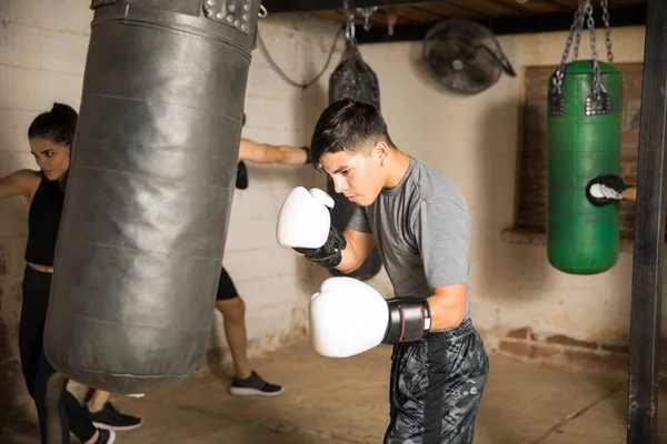 Hombre caja de entrenamiento con un saco de boxeo — Foto de Stock