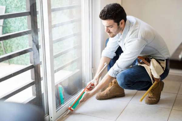 Handyman sealing a window frame — Stock Photo, Image